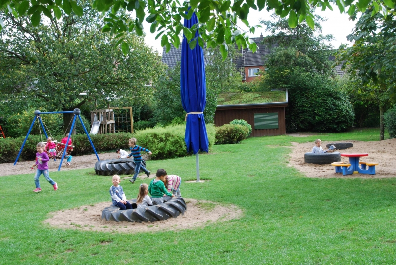 Gartenansicht mit Treckerreifen als Sandkastenumrandung.